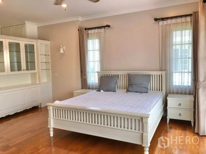 独立式住宅 出租在Mueang Samut Prakan, Samut Prakan - 主卧，木地板，白色床架与床头柜，内置柜体，高窗采光