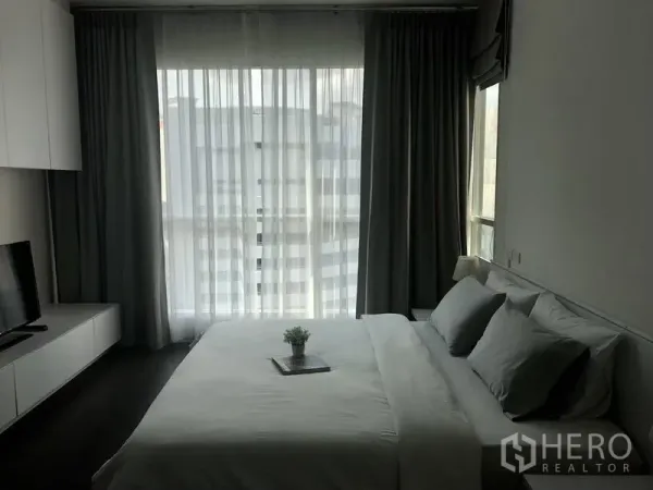 คอนโด ให้เช่าในPathum Wan, Bangkok - ห้องนอนสว่างด้วยหน้าต่างสูงจรดเพดาน ผ้าม่านโปร่ง ตู้ทีวี และเตียงคิงไซส์