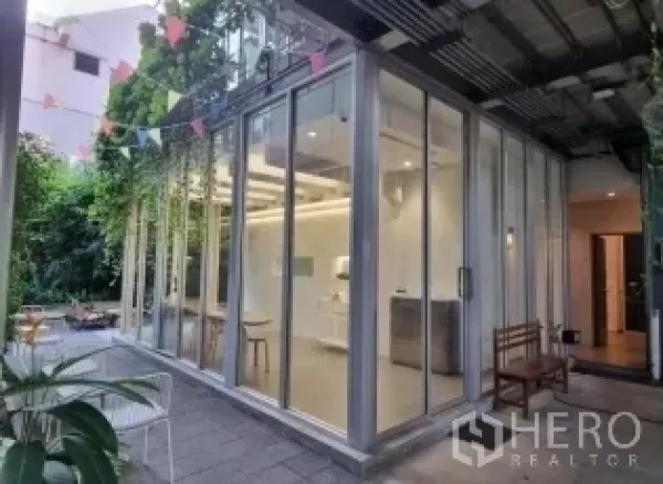 零售空间 出租在Khlong Toei, Bangkok - 玻璃盒子外立面一角，带遮棚露台与绿植座位区