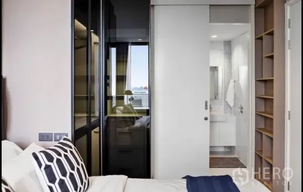 Condominium for rent in Bang Rak, Bangkok - Cozy bedroom with sliding door to a bright bathroom and glass wardrobe.