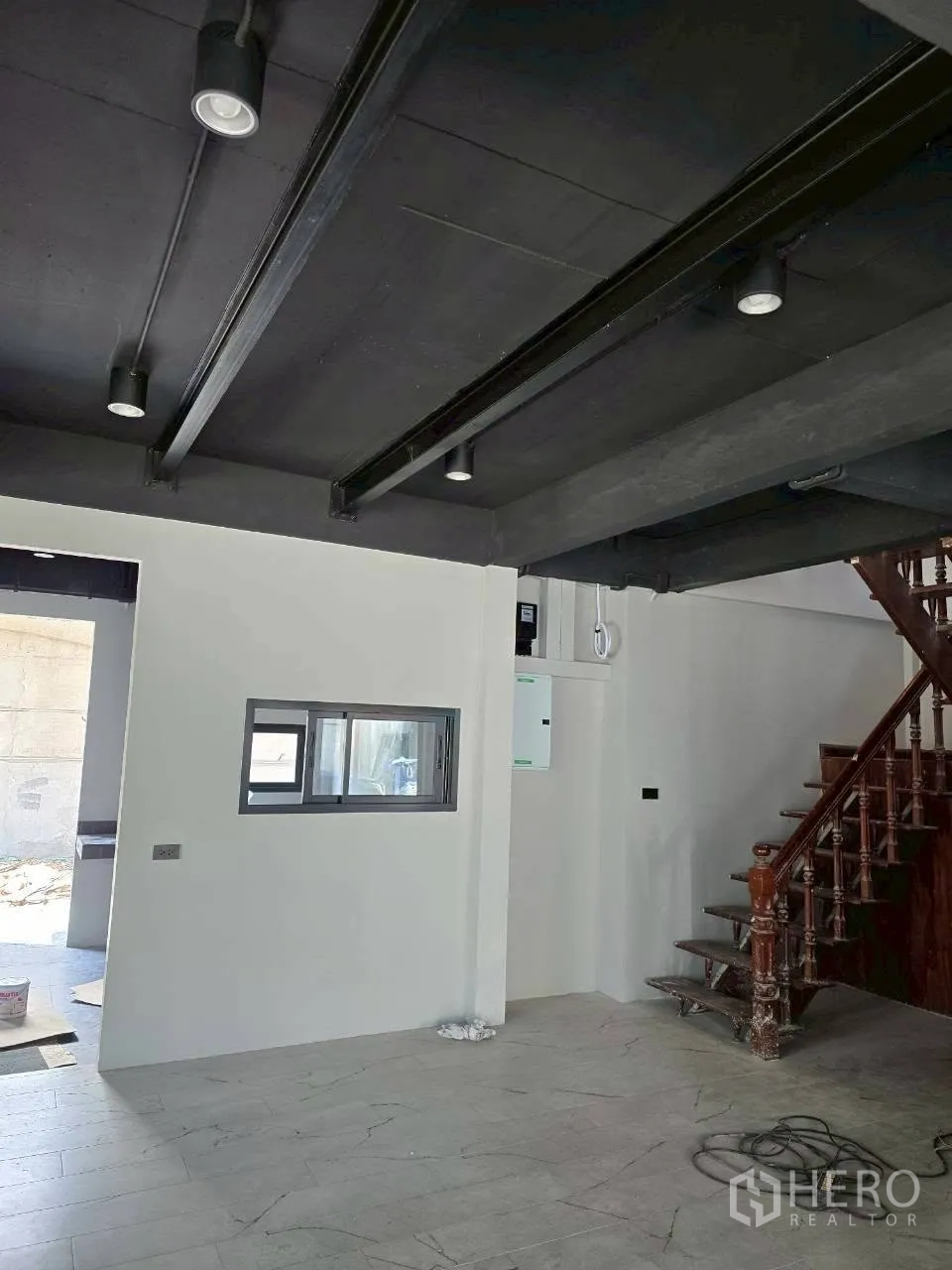 Detached House for rent in Phra Khanong, Bangkok - Living space with exposed beams, service window, and wooden staircase.