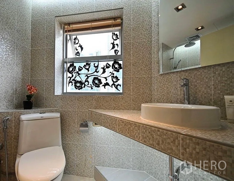 Condominium for rent in Pathum Wan, Bangkok - Bathroom with textured tiles, floral window shade, and countertop basin.