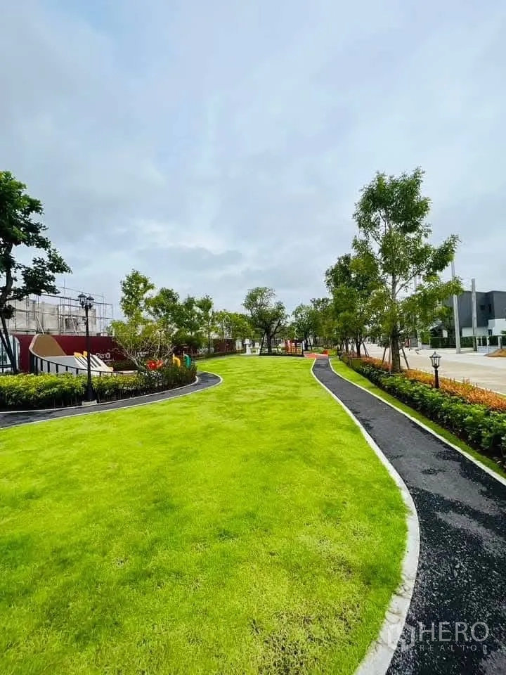 Townhouse for rent in Bang Phli, Samut Prakan - Landscaped community park with a curved jogging path and wide green lawn.