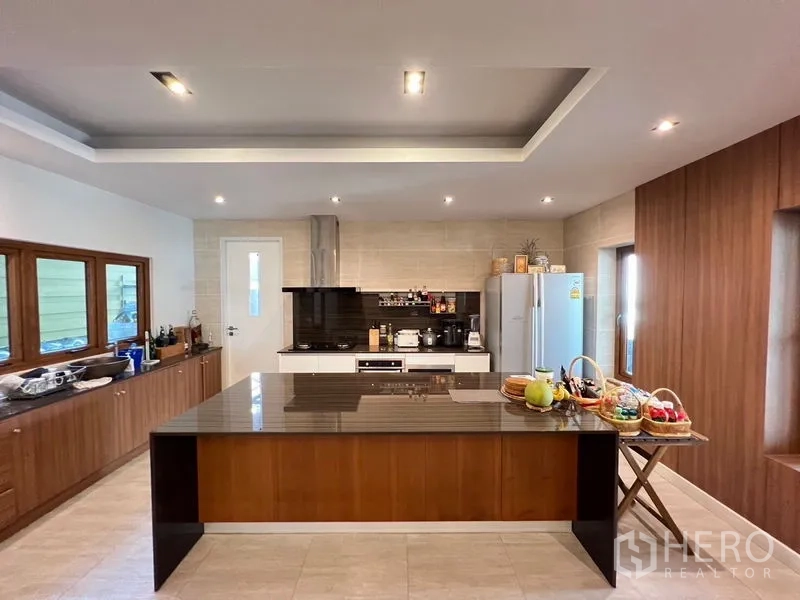 独立式住宅 出售在Chatuchak, Bangkok - 开放式厨房，大型石材岛台、木质橱柜与内置灶台和烟机。