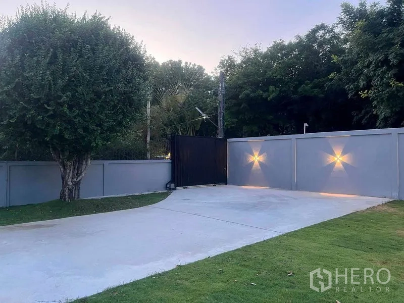 Detached House for sale in Bang Na, Bangkok - Private driveway with sliding gate, wall lights and manicured lawn.