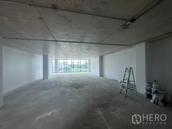 สำนักงาน ให้เช่าในBang Phli, Samut Prakan - ภายในออฟฟิศโล่งยาว มีบันไดและอุปกรณ์ทาสี พร้อมหน้าต่างบานใหญ่ปลายห้อง