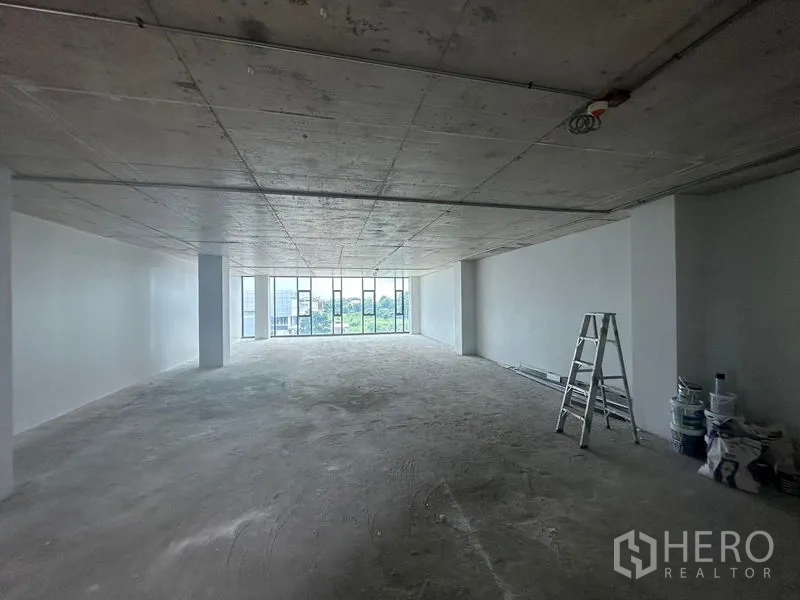 สำนักงาน ให้เช่าในBang Phli, Samut Prakan - ภายในออฟฟิศโล่งยาว มีบันไดและอุปกรณ์ทาสี พร้อมหน้าต่างบานใหญ่ปลายห้อง