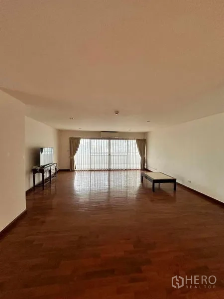 公寓 出租在Bangkok - 宽敞起居室，木地板、茶几、电视与纱帘大窗