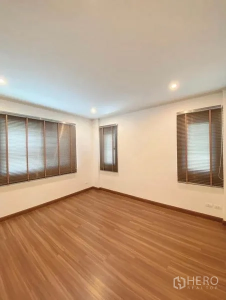 Detached House for sale in Bang Phli, Samut Prakan - Corner bedroom featuring multiple windows with blinds and warm wood-style floors.
