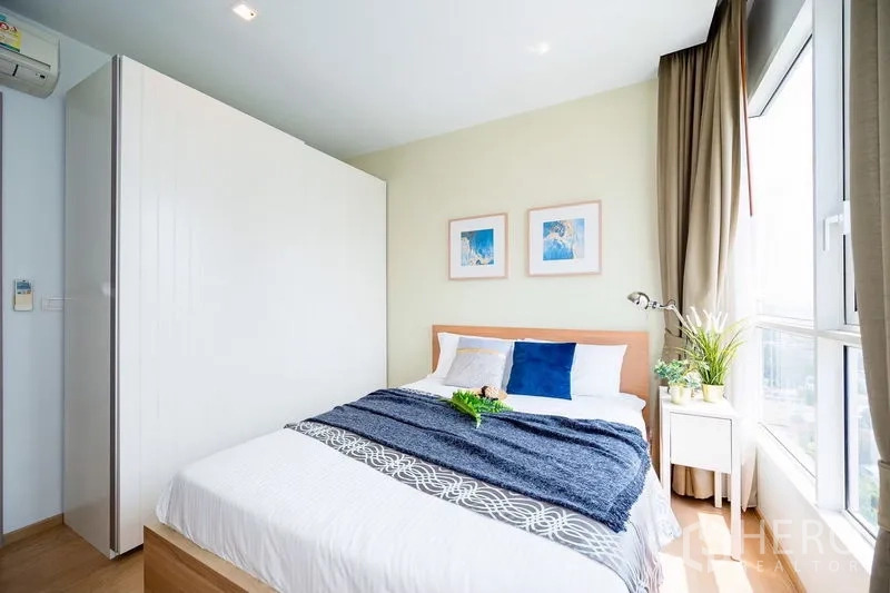 公寓 出租在Watthana, Bangkok - 卧室临落地窗，浅木地板与舒适床品。