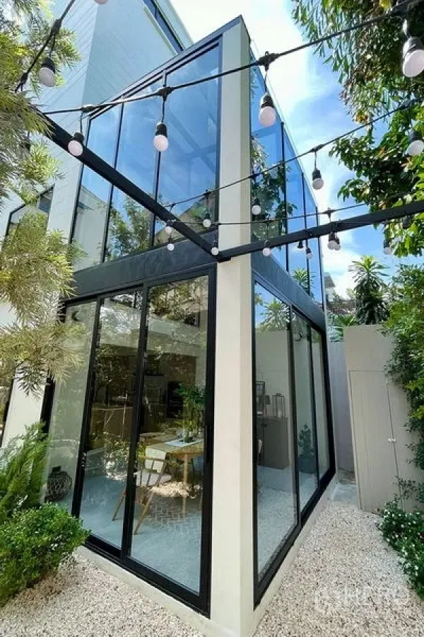 联排别墅 出售在Khlong Toei, Bangkok - 现代立面转角，落地玻璃与庭院串灯相映成趣。