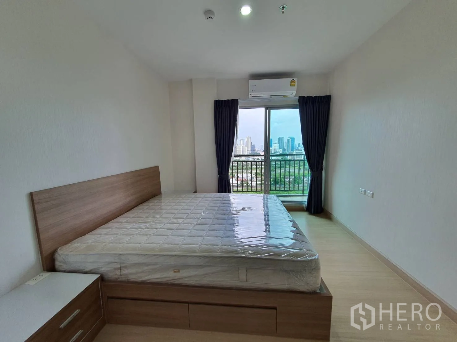 คอนโด for rent in Huai Khwang, Bangkok - ห้องนอนเตียงยกพื้น พร้อมระเบียงชมวิวเมืองผ่านประตูกระจกสไลด์