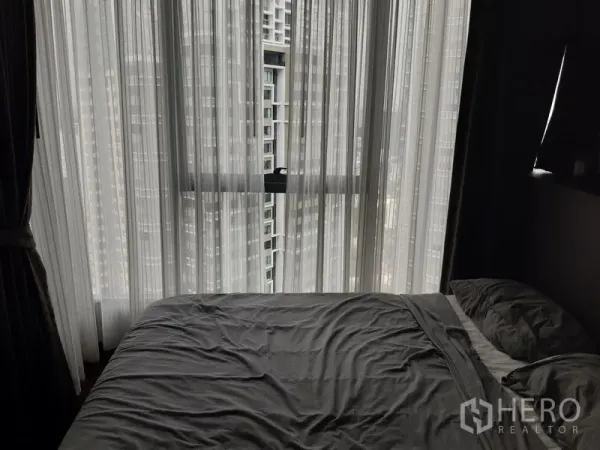 คอนโด ให้เช่าในKhlong Toei, Bangkok - ห้องนอนปูผ้าปูสีเทา มีหน้าต่างกระจกเต็มบาน ผ้าม่านโปร่ง และวิวเส้นขอบฟ้าเมือง