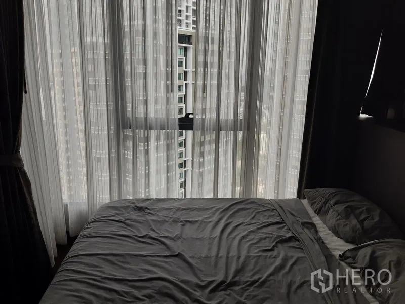 คอนโด ให้เช่าในKhlong Toei, Bangkok - ห้องนอนปูผ้าปูสีเทา มีหน้าต่างกระจกเต็มบาน ผ้าม่านโปร่ง และวิวเส้นขอบฟ้าเมือง