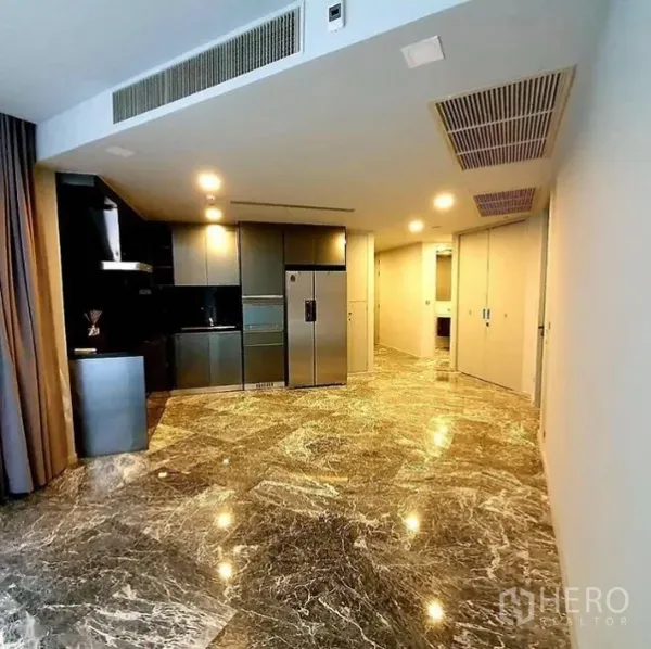 Condominium for rent or sale in Watthana, Bangkok - Open-plan living area with marble flooring and a sleek built-in kitchen in a Phrom Phong condo.