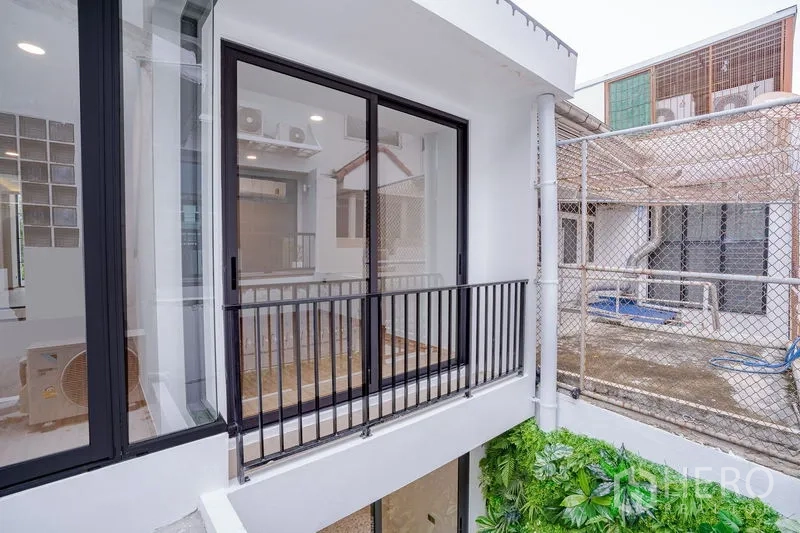 Townhouse for sale - Small balcony with black railing overlooking the internal lightwell and greenery.