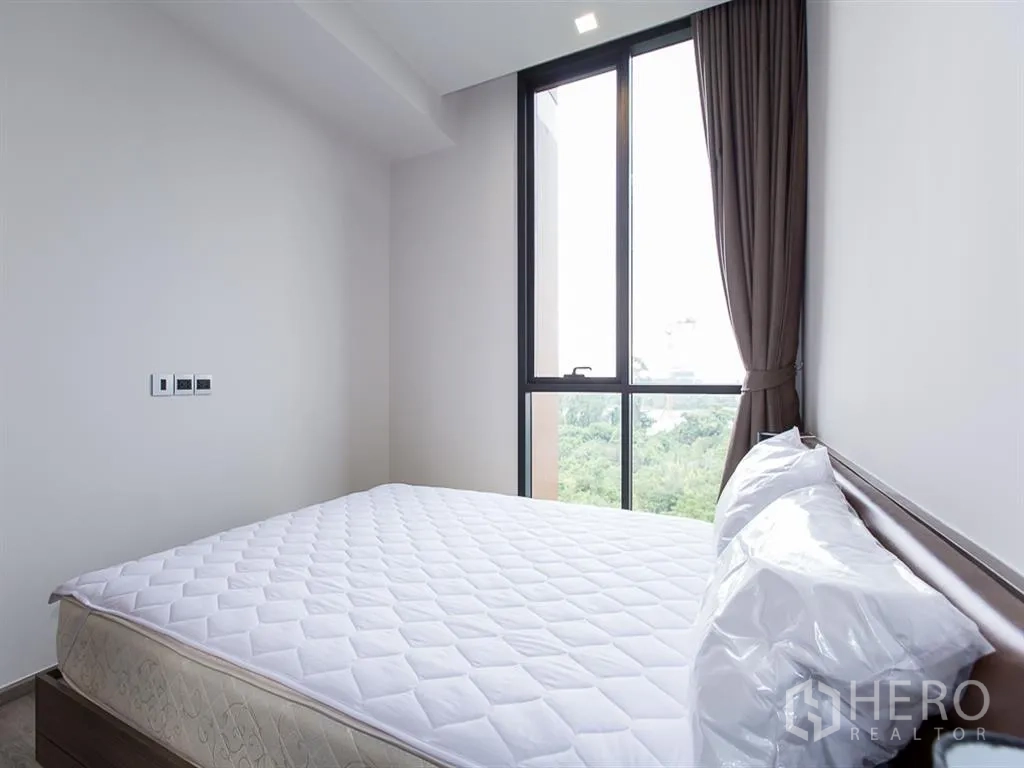 คอนโด for rent in Watthana, Bangkok - มุมห้องนอนแสดงหน้าต่างสูงจรดเพดานพร้อมผ้าม่านและวิวเรือนยอดไม้