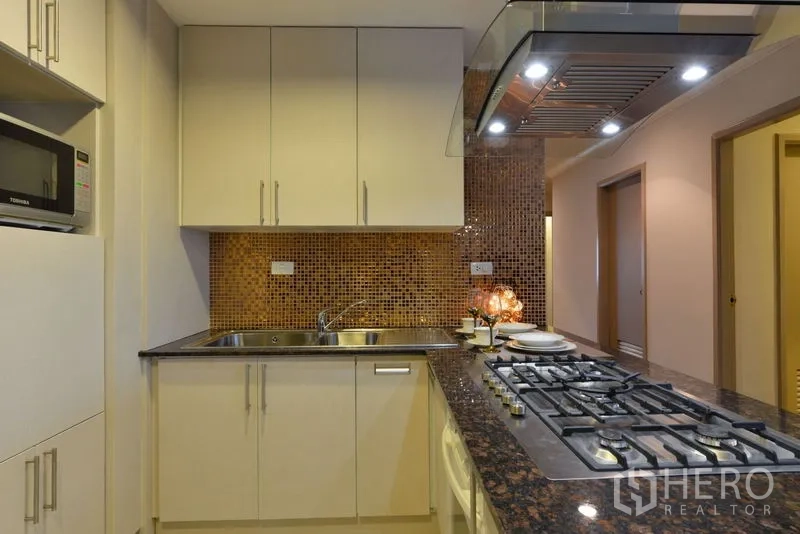 คอนโด ให้เช่าในWatthana, Bangkok - พื้นที่เตรียมอาหารพร้อมอ่างล้างจานคู่ ตู้เก็บของเหลือเฟือ และเตาแบบไอส์แลนด์ใต้ฮูดโค้ง