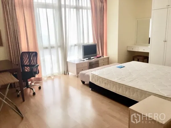 Condominium for rent in Khlong Toei, Bangkok - Spacious bedroom with floor-to-ceiling windows, desk, TV stand, and soft curtains.