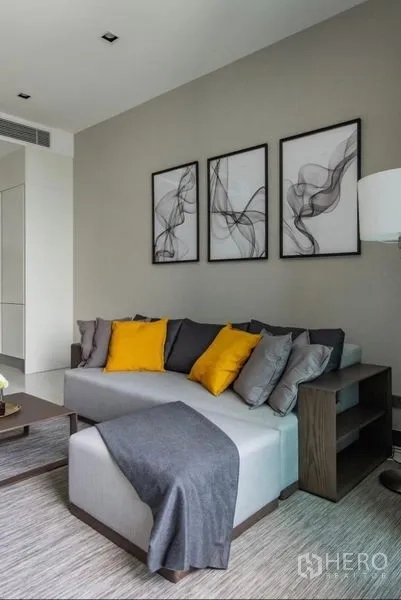 คอนโด ให้เช่า - โซฟา L-Shape หมอนสีเหลือง และกรอบภาพศิลป์แบบนามธรรมสามชิ้น