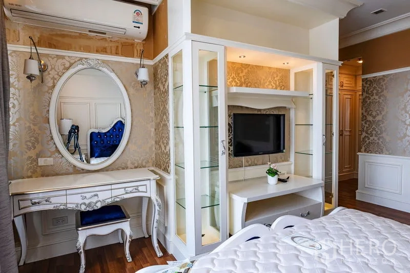 Condominium for rent in Watthana, Bangkok - Vanity corner with oval mirror, TV unit with glass shelving and classic white furniture.
