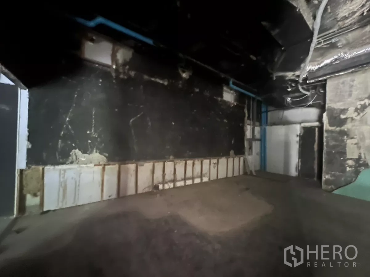 零售空间 出租在Khlong Toei, Bangkok - 后场空间，深色墙面与蓝色管道，适合仓储或设备间。