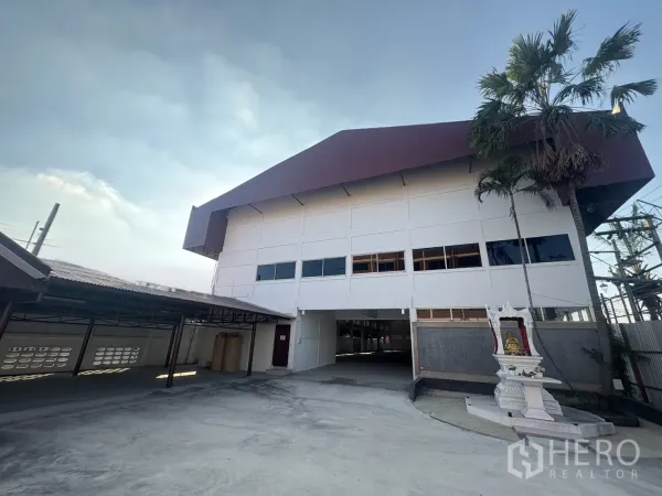 คลังสินค้า ให้เช่าในBang Phli, Samut Prakan - มุมมองด้านหน้าโกดังสีขาวหลังคาสีแดงเลือดหมู ทางเข้าพร้อมศาลพระภูมิในบางพลี