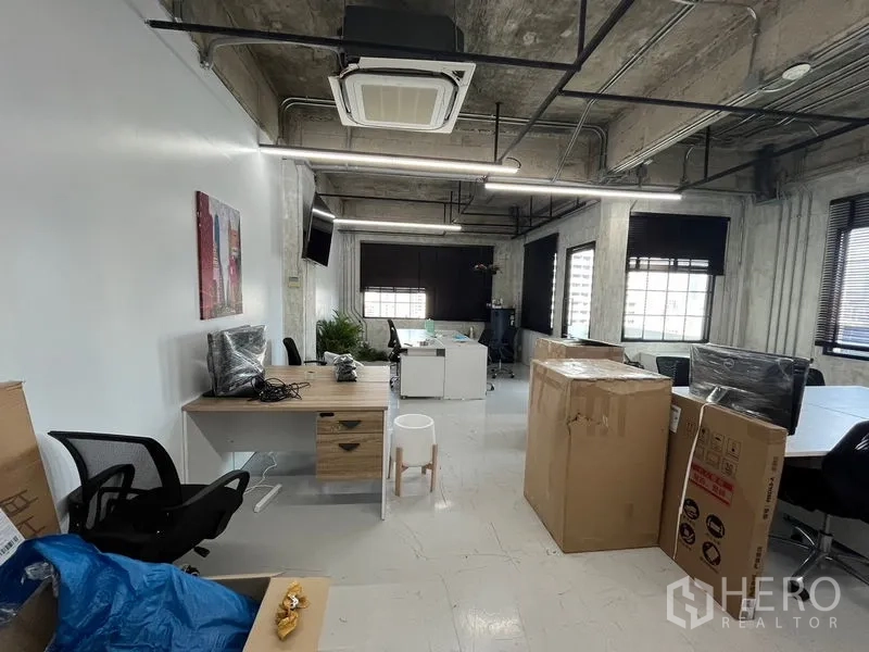 办公空间 出租在Khlong Toei, Bangkok - 开放式办公区，外露管线与嵌入式空调，办公桌与纸箱，线性LED照明。