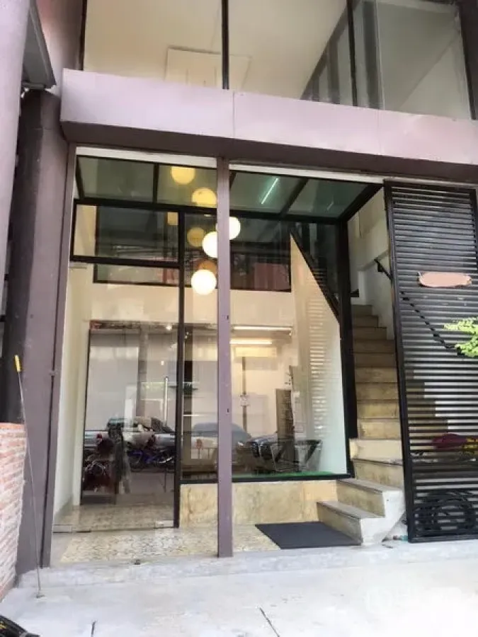 零售空间 出租在Khlong Toei, Bangkok - 双层挑高玻璃门面，黑色框架，入口台阶与旁侧楼梯。