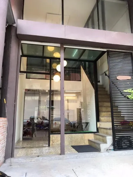 零售空间 出租在Khlong Toei, Bangkok - 双层挑高玻璃门面，黑色框架，入口台阶与旁侧楼梯。