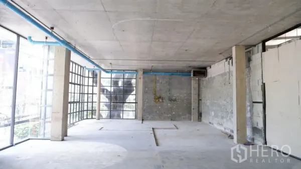 零售空间 出租在Watthana, Bangkok - 宽敞毛坯室内，混凝土顶与管线可见，转角玻璃适合显眼招牌。