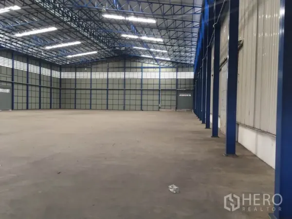 Warehouse for rent in Pak Kret, Nonthaburi - Spacious high-ceiling warehouse interior with blue steel trusses and bright LED lighting.