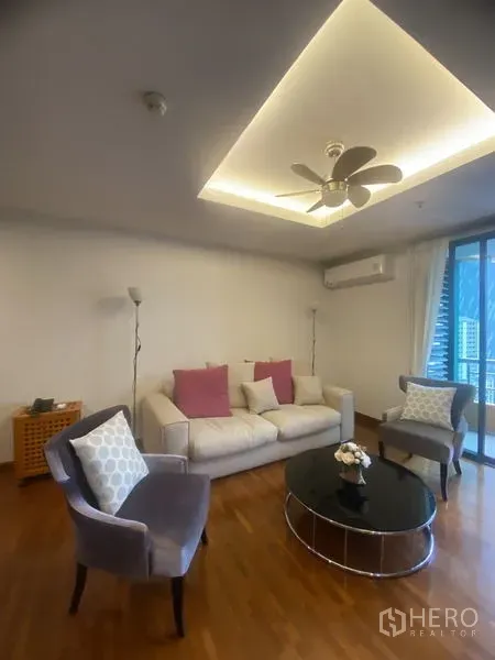 คอนโด ให้เช่าในPathum Wan, Bangkok - ห้องนั่งเล่น โซฟาและเก้าอี้ล้อมโต๊ะกลมสีดำ ใต้ฝ้าซ่อนไฟและประตูกระจกออกระเบียง