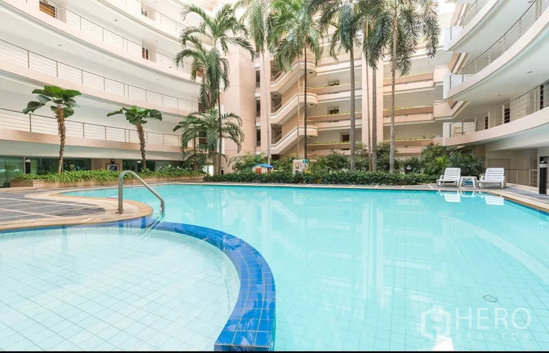Condominium for rent in Pathum Wan, Bangkok - Condominium resort-style swimming pool in an open atrium with palm trees and sun loungers.