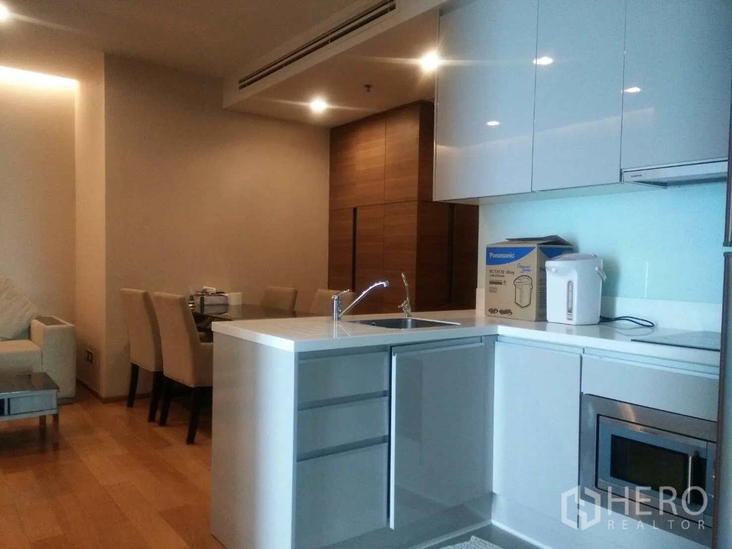 Condominium for rent in Ratchathewi, Bangkok - Open-plan living with sleek white kitchen, island sink, dining area and sofa