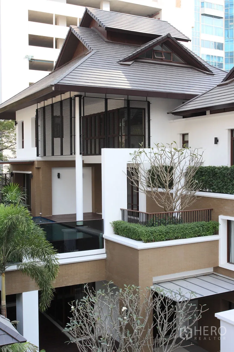 Detached House for rent in Khlong Toei, Bangkok - Contemporary Thai-style detached house exterior with layered roof, glass railing and landscaped planters.