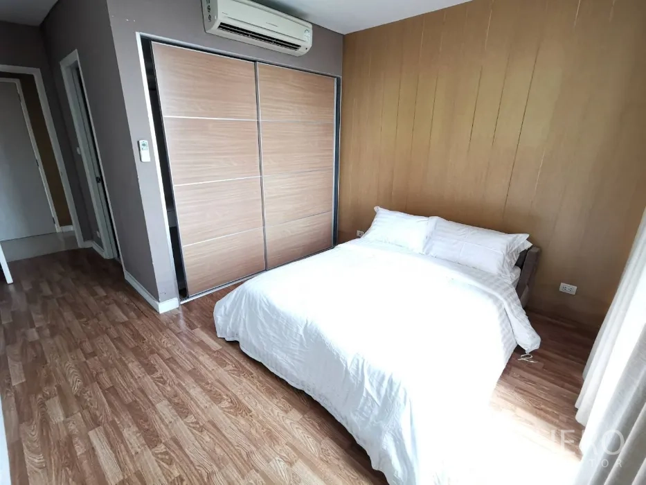 Condominium for rent in Watthana, Bangkok - Cozy guest bedroom with double bed, wood accent wall, sliding wardrobe, and wood flooring.