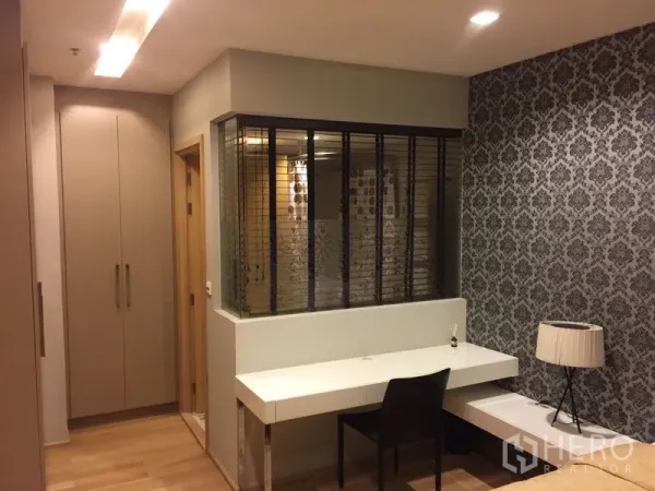 คอนโด ให้เช่าในKhlong Toei, Bangkok - มุมโต๊ะทำงานและตู้เสื้อผ้าบิลท์อิน ข้างผนังกระจกกั้นห้อง วอลล์เปเปอร์ลาย และพื้นไม้