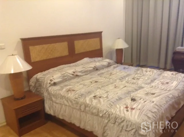 คอนโด ให้เช่าหรือขายในDin Daeng, Bangkok - ห้องนอนหลักเตียงคิงไซซ์ โต๊ะข้างเตียงพร้อมโคมไฟ และผ้าม่านทึบแสง