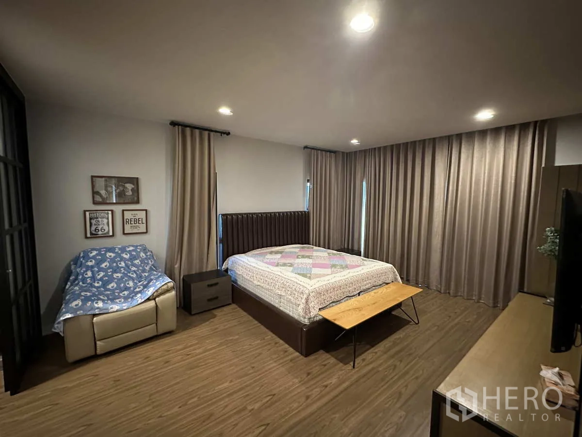 บ้าน ให้เช่าหรือขายในLam Luk Ka, Pathum Thani - ห้องนอนมาสเตอร์ขนาดใหญ่ เตียงคิง ผ้าม่านเต็มความสูง และมุมนั่งเล่น.