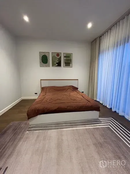 Detached House for rent in Bang Kapi, Bangkok - Minimalist bedroom with brown bedding and floor‑to‑ceiling sheer curtains