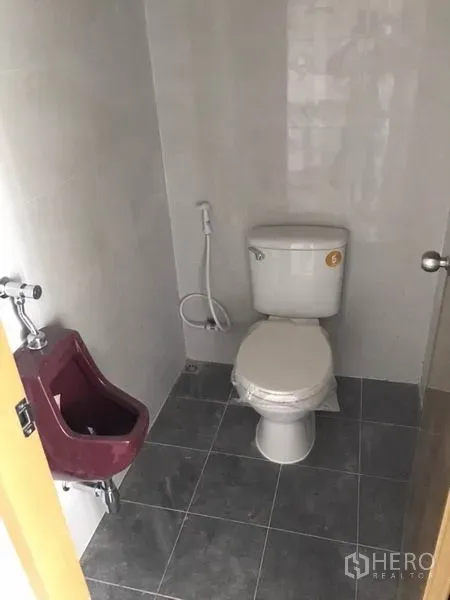 零售空间 出租在Bang Kapi, Bangkok - 卫生间配坐便器、小便池与喷枪，灰色地砖铺设。