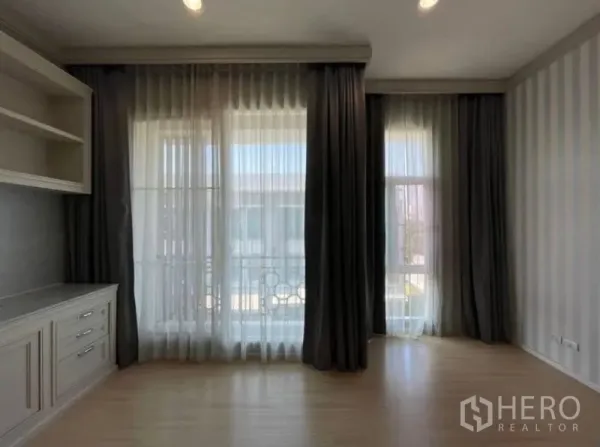 ทาวน์เฮาส์ ขาย - ห้องนอนสว่างพร้อมหน้าต่างแบบฟลอร์ทูซีลิ่ง ผ้าม่านสองชั้น และตู้บิวท์อิน พื้นลามิเนต