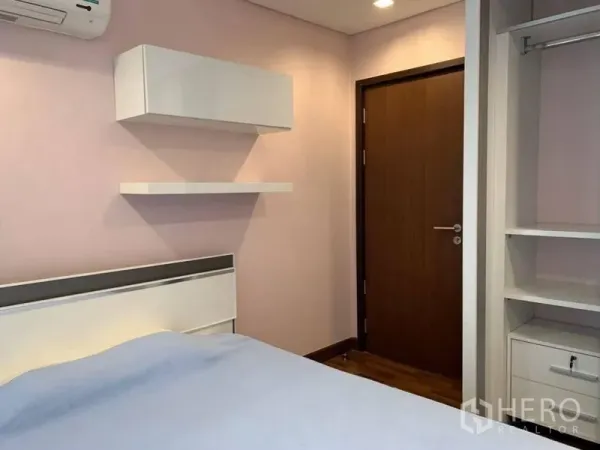 Condominium for rent in Watthana, Bangkok - Second bedroom with shelves, wardrobe and soft pastel walls.