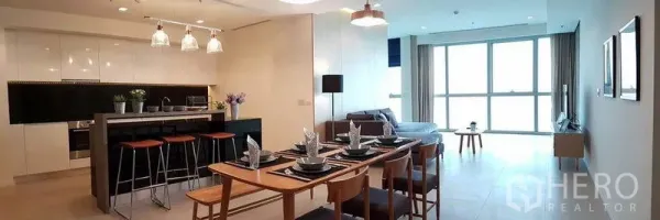 Condominium for rent in Khlong San, Bangkok - Panoramic view of open-plan island kitchen, dining table and living area with large windows.