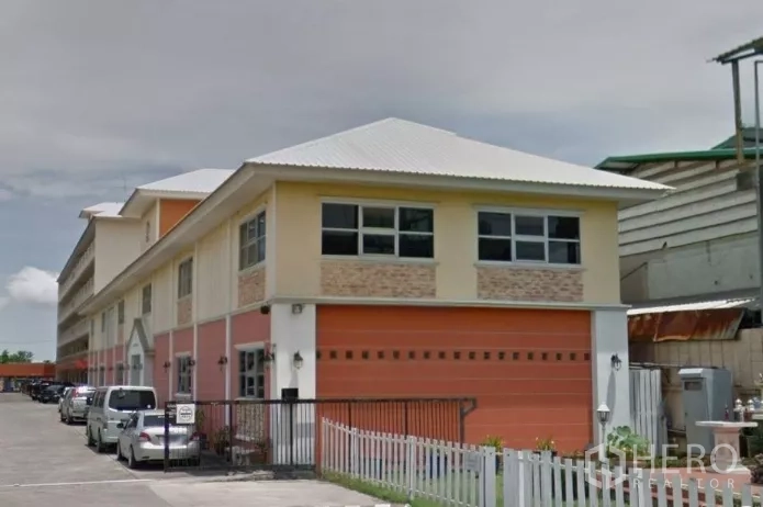 Warehouse for rent in Krathum Baen, Samut Sakhon - Two‑storey warehouse exterior with orange roller door, fenced entry and parking area.