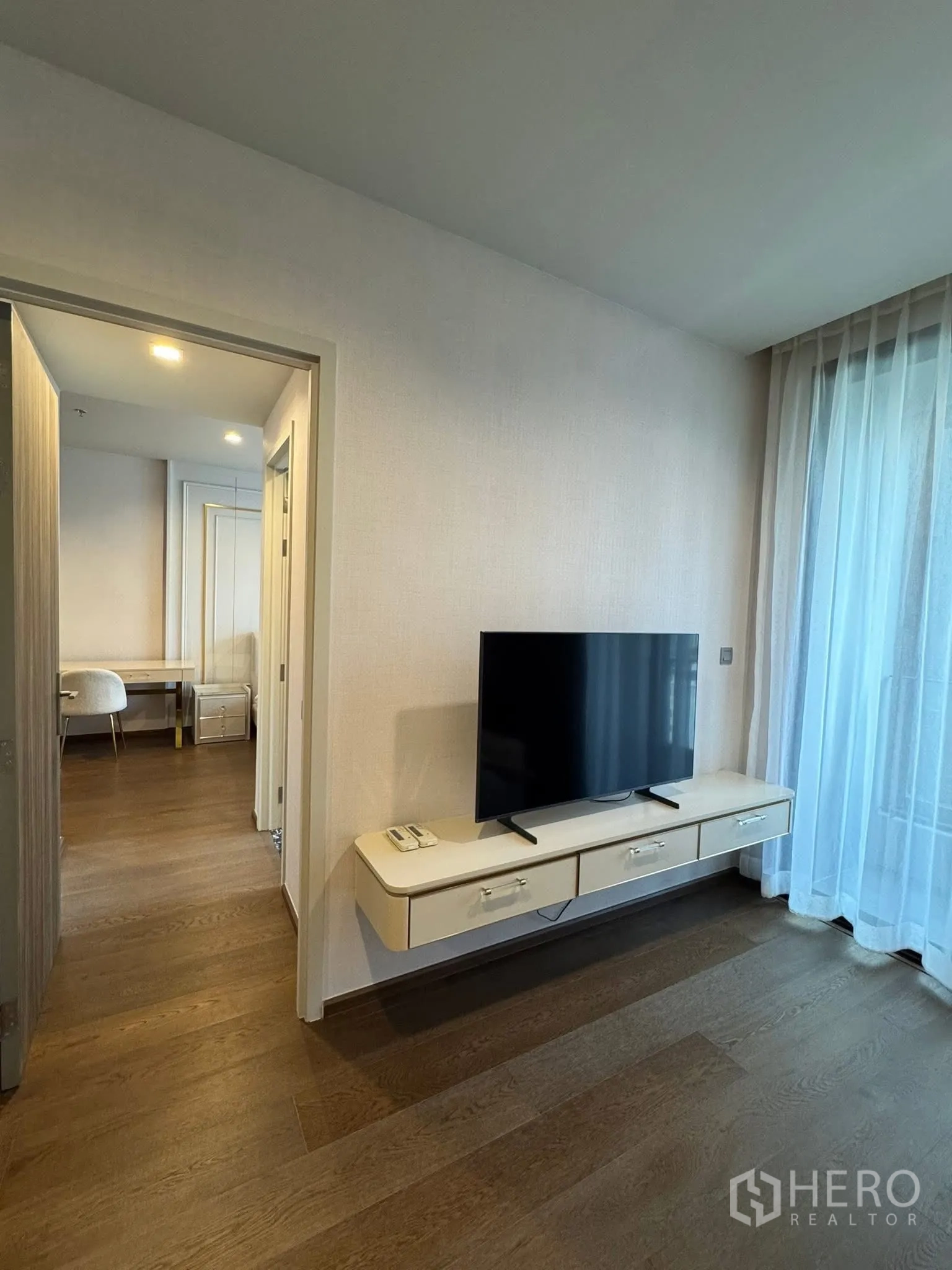 คอนโด for rent in Khlong Toei, Bangkok - ผนังทีวีพร้อมชั้นแขวนลอยและผ้าม่านโปร่ง