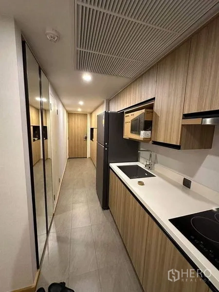 公寓 出租在Pathum Wan, Bangkok - 廊式厨房，木质橱柜、灶台、微波炉与冰箱