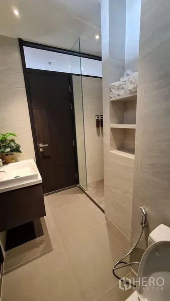 Condominium for rent - Second bathroom featuring glass shower, built-in shelves and handheld bidet spray.
