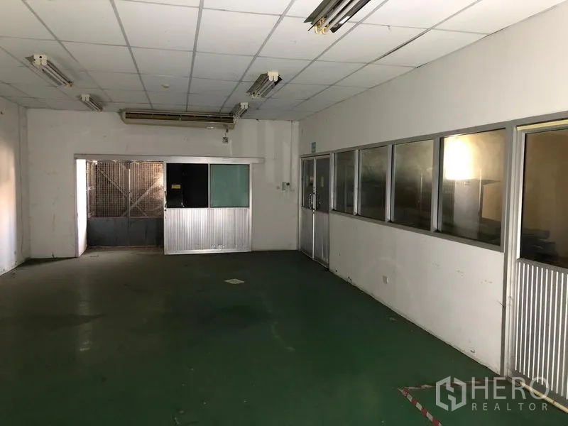 Factory for rent or sale in Khlong Luang, Pathum Thani - Workshop area with green epoxy floor, partition windows and sliding door to service zone.
